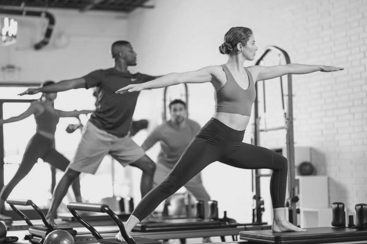 Group class with arms extended on the reformers at Pilates On Fifth