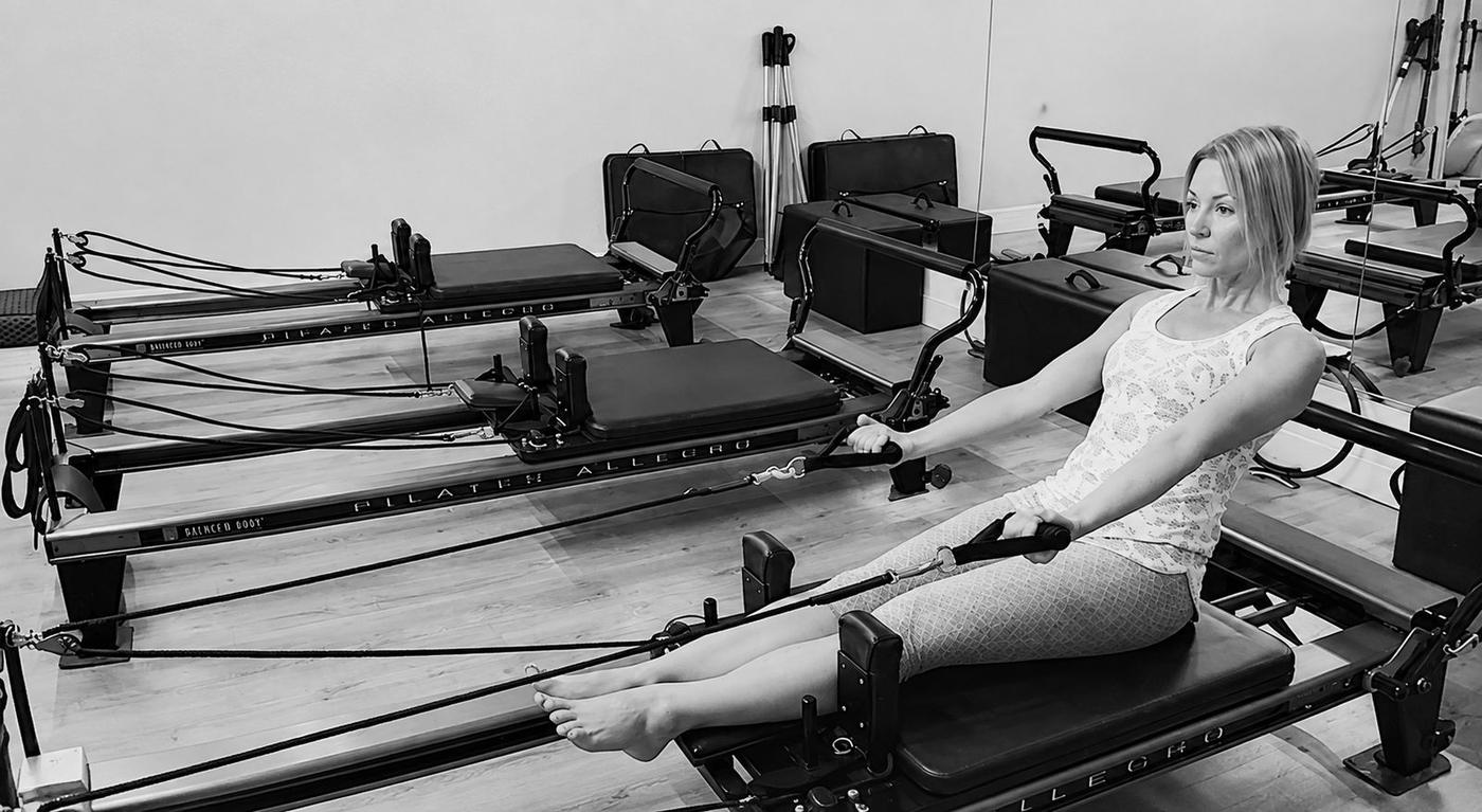 Client on the reformer with an instructor nearby
