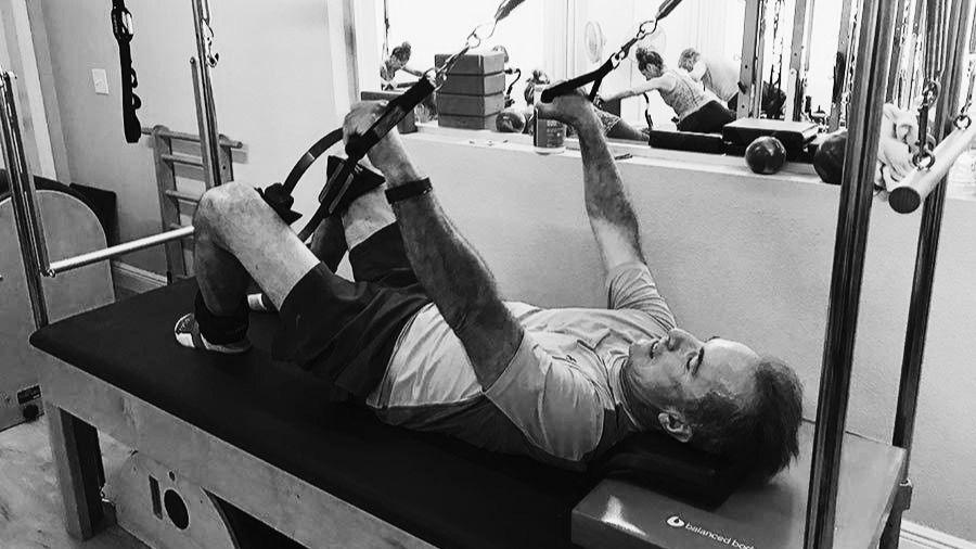 Instructor guiding a student on the reformer