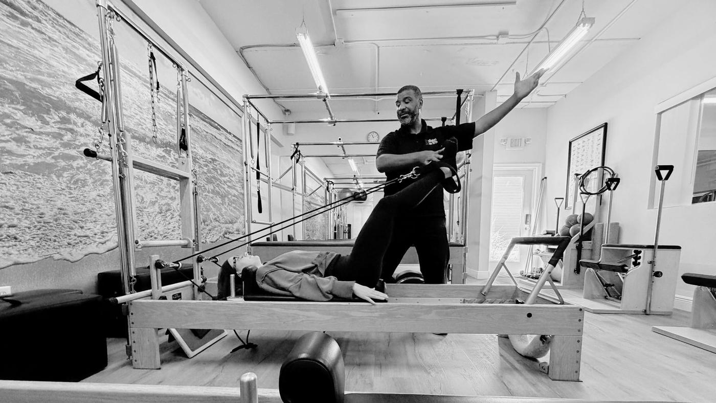 Trainer assisting a client on the reformer
